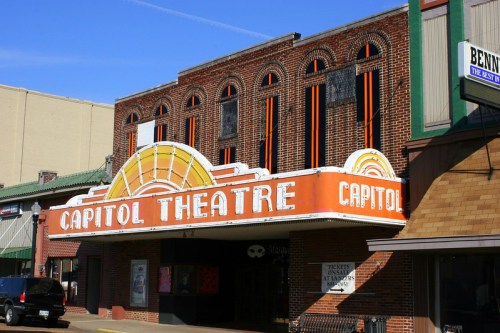 Historic Capitol Theatre with a vibrant marquee, featuring orange and white design, set against a clear blue sky.