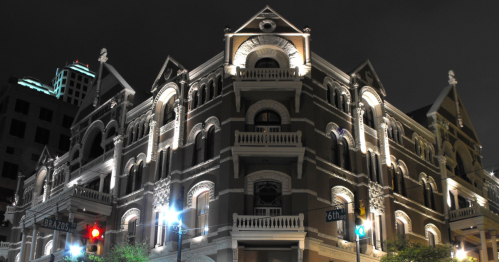 Historic building illuminated at night, showcasing intricate architectural details and balconies.