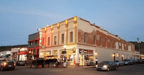 Historic building with a mix of brick and painted walls, featuring shops and a hotel sign, set in a small town at dusk.