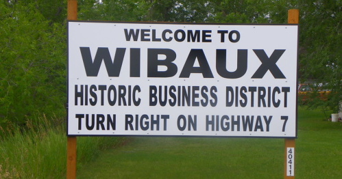 Sign welcoming visitors to Wibaux, highlighting the historic business district and directions to turn right on Highway 7.