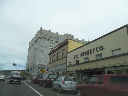 Street view featuring a J.C. Penney store and a tall, historic building under a cloudy sky.