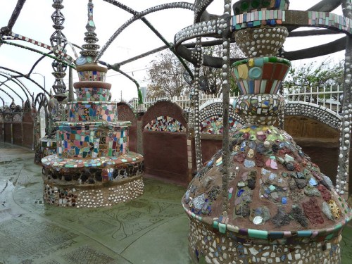 Colorful mosaic structures in a whimsical outdoor space, featuring intricate designs and patterns.