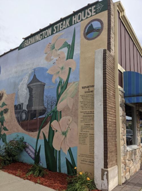 Mural on the side of a building featuring flowers and a water tower, labeled "Farmington Steak House."
