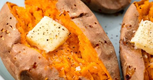 Baked sweet potatoes topped with a pat of butter and sprinkled with black pepper on a light blue plate.
