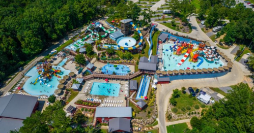 Aerial view of a vibrant water park with slides, pools, and lounging areas surrounded by greenery.