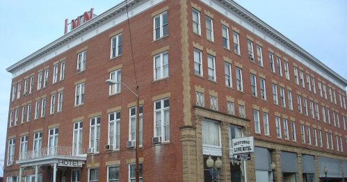 Historic brick hotel building with large windows and a sign reading "Huntington Hotel" on the corner.