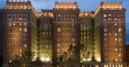 Historic brick hotel illuminated at night, showcasing its architectural details and surrounding trees.