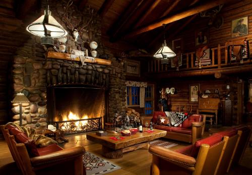 Cozy log cabin interior with a stone fireplace, wooden beams, and rustic furniture, creating a warm, inviting atmosphere.