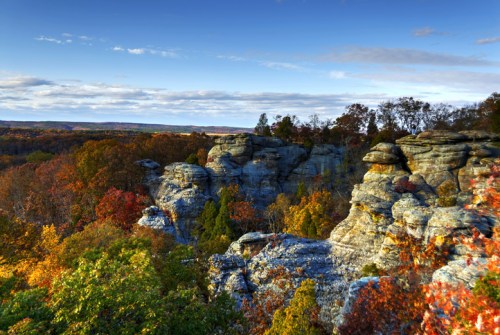 Scenic view of rocky formations surrounded by vibrant autumn foliage under a clear blue sky.