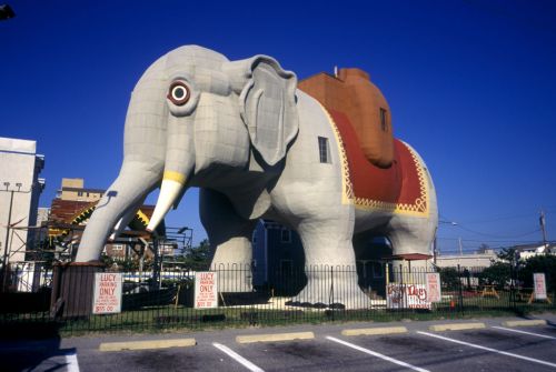 A large, whimsical elephant-shaped building with a red saddle, set against a clear blue sky.