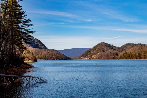 A serene lake surrounded by mountains and trees under a clear blue sky.
