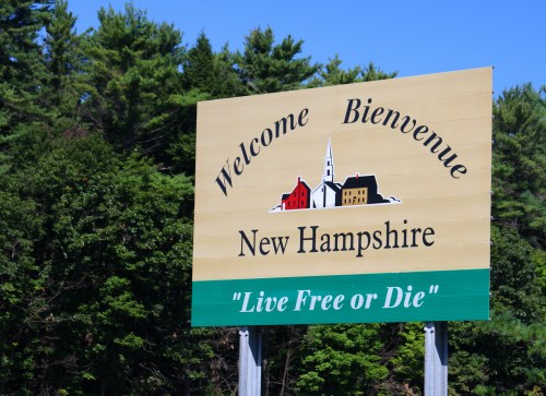 Welcome sign for New Hampshire featuring the phrase "Live Free or Die" and a depiction of a church and houses.