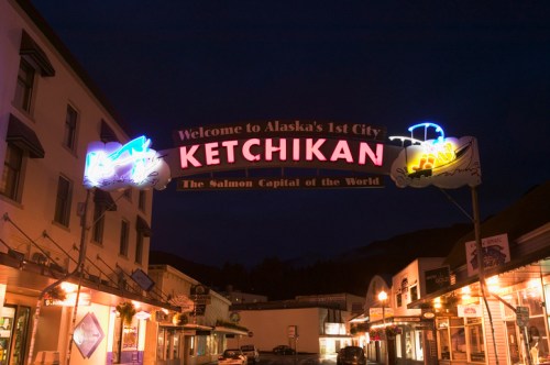 Neon sign welcoming visitors to Ketchikan, Alaska, with the tagline "The Salmon Capital of the World" at night.