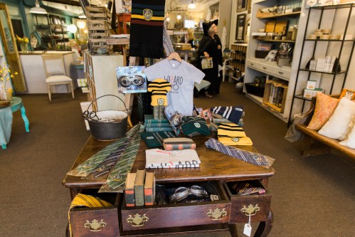 A cozy shop display featuring clothing, accessories, and decor items on a wooden table.