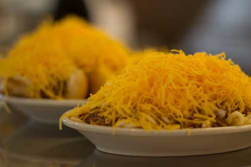 Two plates of food topped with a generous layer of shredded yellow cheese.