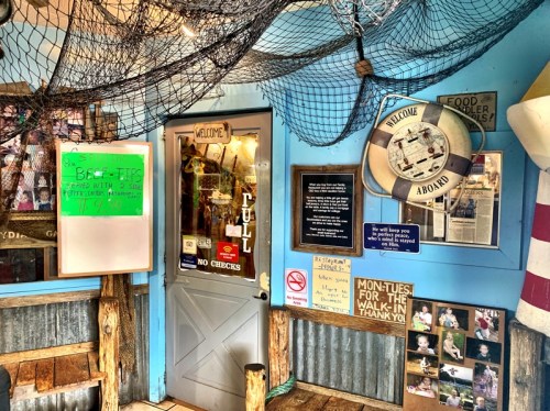Cozy restaurant entrance with nautical decor, a welcome sign, and a chalkboard menu.