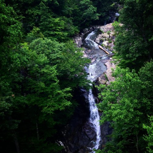 A serene waterfall cascading through rocky terrain, surrounded by lush green trees.