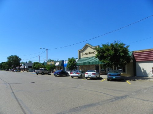 A sunny street view featuring Hazen Drug and parked cars along a small-town storefront.