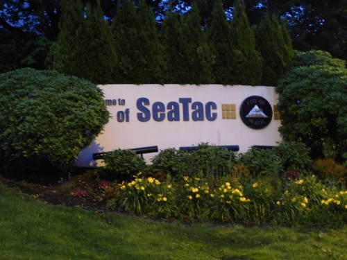 Welcome sign for SeaTac, surrounded by greenery and flowers, with the city emblem displayed.