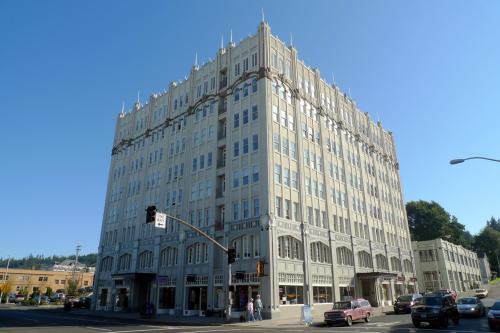 Historic multi-story building with ornate architecture, clear blue sky, and street traffic in the foreground.