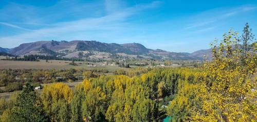 A scenic view of rolling hills and vibrant autumn trees under a clear blue sky.