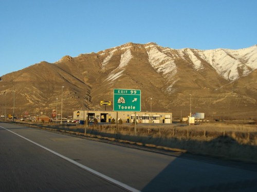 Highway exit sign for Tooele, Utah, with mountains in the background and clear blue sky.