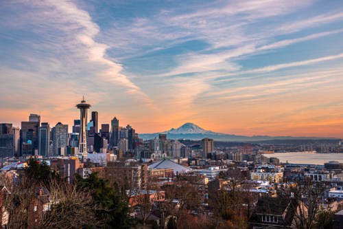A panoramic view of Seattle's skyline with Mount Rainier in the background during sunset.