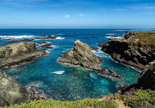 A scenic coastal view featuring rocky formations and clear blue waters under a bright sky.