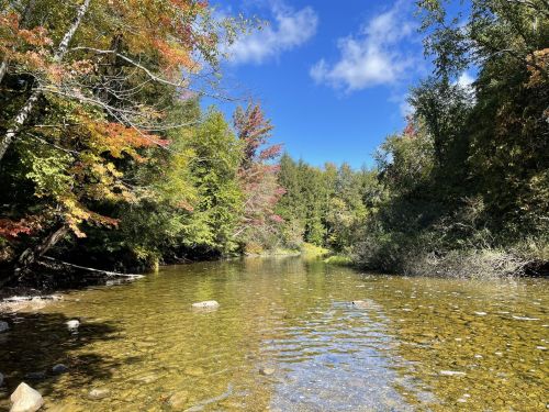 A serene river scene surrounded by colorful autumn foliage under a clear blue sky.