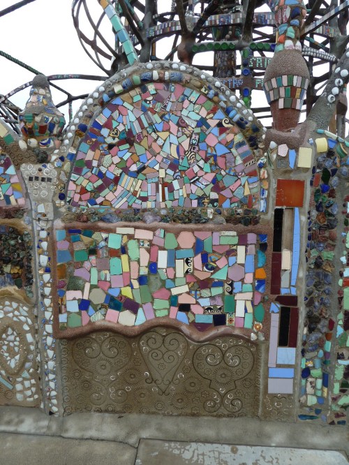 Colorful mosaic wall featuring various shapes and materials, with intricate patterns and textures.