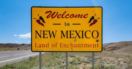 New Mexico state sign with the slogan Land of Enchantment and chili peppers on it