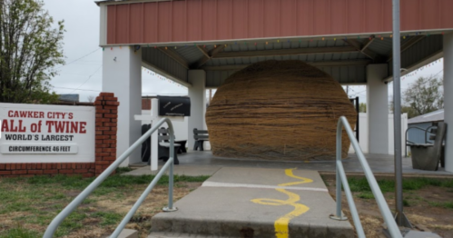 A large ball of twine displayed under a shelter in Cawker City, Kansas, with a sign indicating it's the world's largest.
