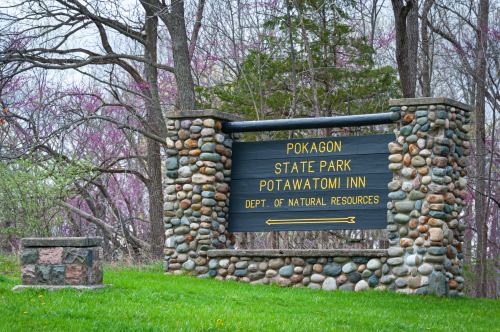 Sign for Pokagon State Park and Potawatomi Inn, surrounded by trees and grass.