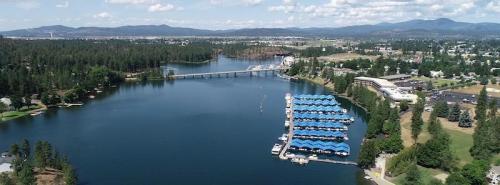 Aerial view of a serene lake with boat docks, surrounded by trees and mountains under a clear blue sky.