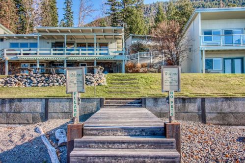 A wooden pathway leads to a lakeside property with signs welcoming guests and indicating no pets allowed.