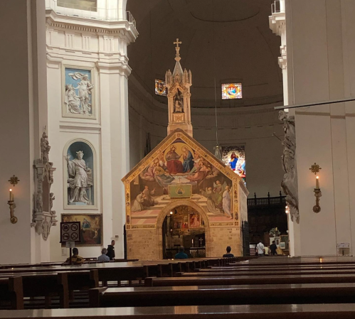 Interior of a church featuring a decorated altar, stained glass windows, and wooden pews.
