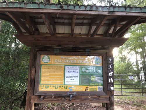 Sign for the Old River Trail in Milton, featuring park information and recreational guidelines.