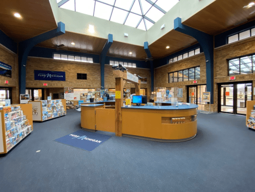 Interior of a visitor center with a circular information desk, brochures, and large windows letting in natural light.