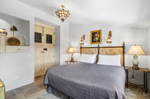 Cozy bedroom featuring a large bed, decorative lamps, and stylish wall art in a softly lit, neutral-toned space.
