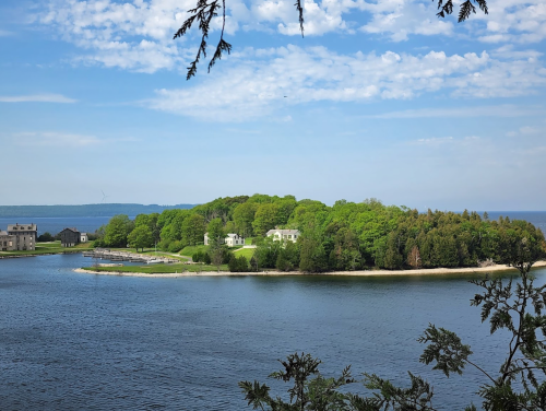 A serene view of a lush green island surrounded by calm water under a clear blue sky.
