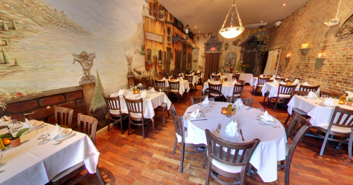 Elegant restaurant interior with white tablecloths, wooden chairs, and mural-covered walls, creating a cozy atmosphere.