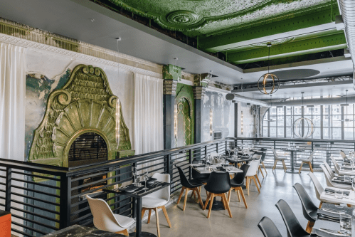 Stylish restaurant interior with ornate green ceiling, modern furniture, and elegant decor.