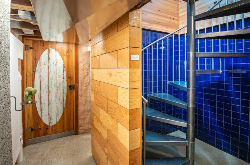 A modern interior featuring a spiral staircase, wooden walls, and a green decorative object on a wall.