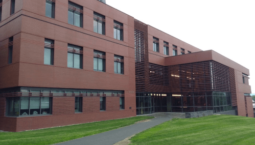 Modern brick building with large windows and a landscaped path in front.