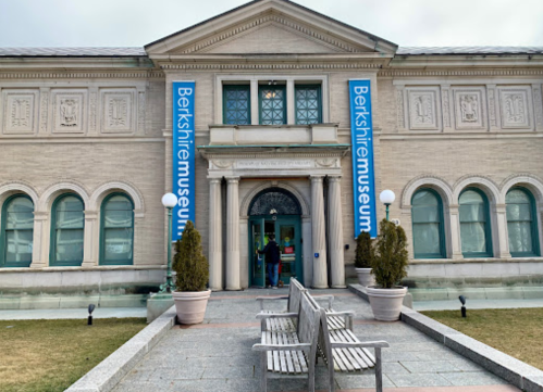 Entrance of the Berkshire Museum, featuring large banners and a grassy area with benches in front.