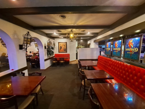 Interior of a cozy restaurant featuring red booths, wooden tables, and decorative lighting. Stained glass windows visible.