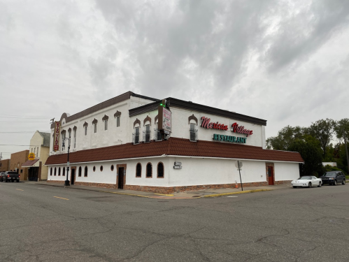 A corner view of a restaurant with a white exterior and a brown roof, featuring arched windows and a sign that reads "Morris Village."