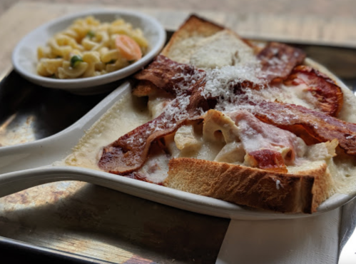 A plate of baked pasta with bacon on toast, served with a side of macaroni salad.