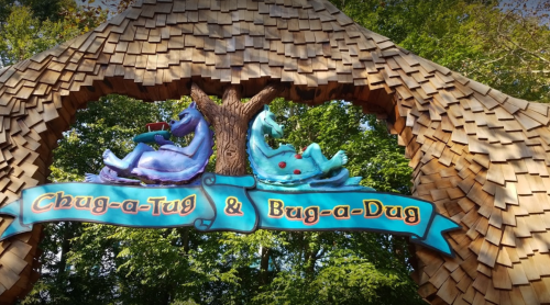 Colorful sign reading "Chug-a-Tug & Bug-a-Dug" under a wooden arch with whimsical characters, surrounded by trees.