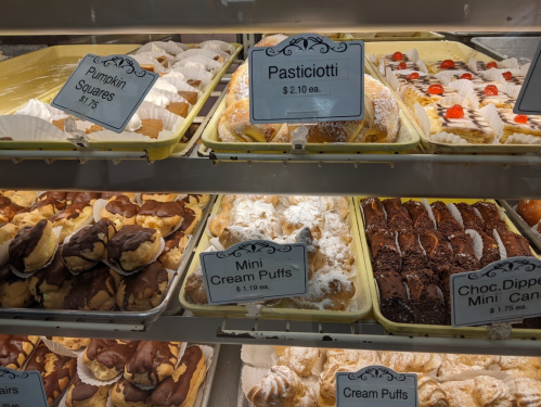 A display case filled with various pastries, including pasticiotti, mini cream puffs, and chocolate-dipped treats.